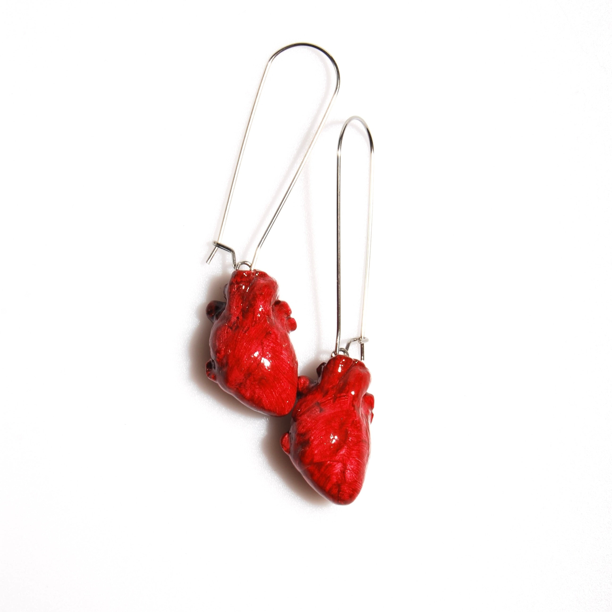 Orecchini cuore anatomico rosso con monachelle lunghe acciaio appoggiati su fondo bianco