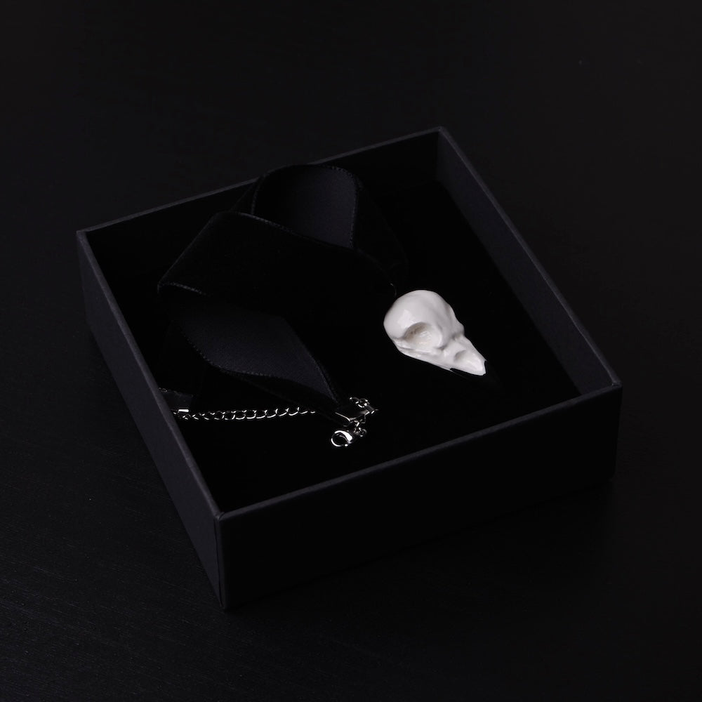 choker run velluto nero con pendente miniatura di teschio di corvo dentro una scatolina nera