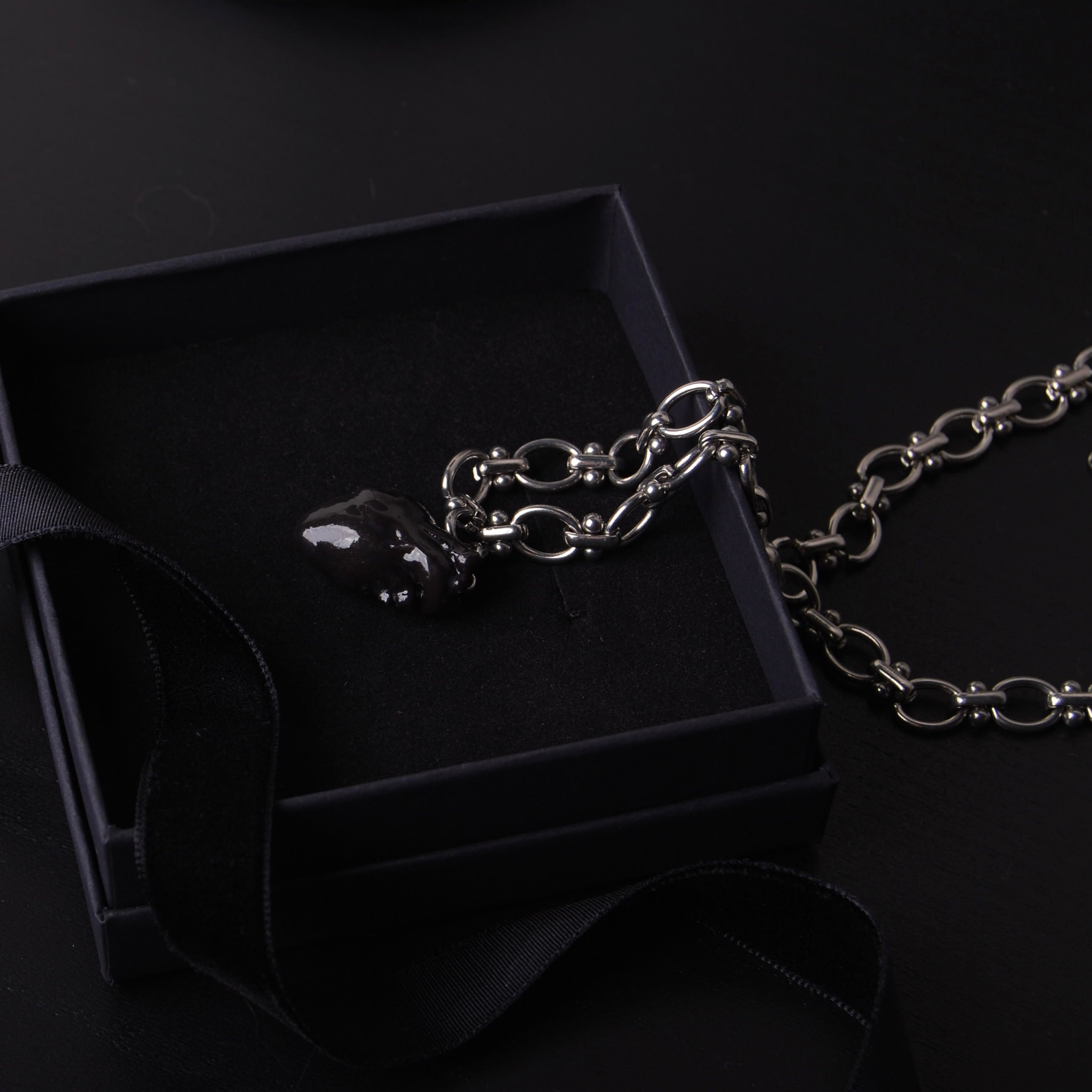 collana catena spessa con pendente cuore anatomico nero dentro una scatolina nera con nastro nero