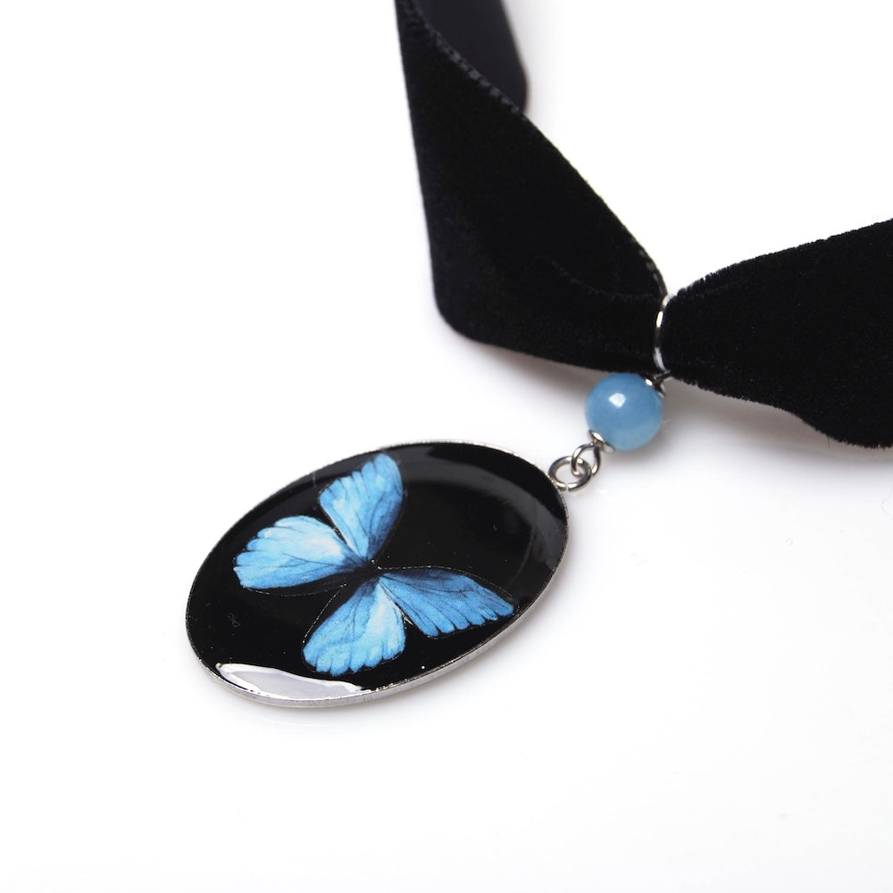 pendente ovale con farfalla blu appeso a choker in velluto nero con perlina di acquamarina, dettaglio del pendente