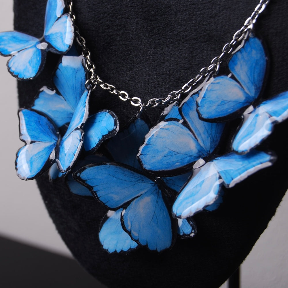 collana con sciame di farfalle blu su espositore, particolare delle ali