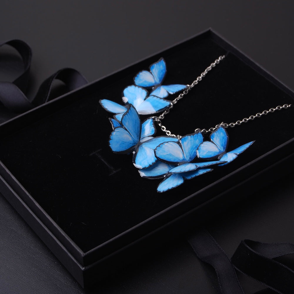 collana con sciame di farfalle blu dentro scatola nera