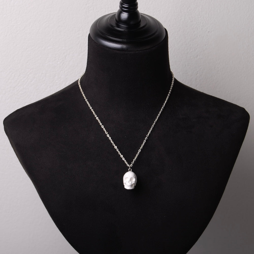 collana con catena sottile e pendente teschio bianco, su busto espositore in velluto nero