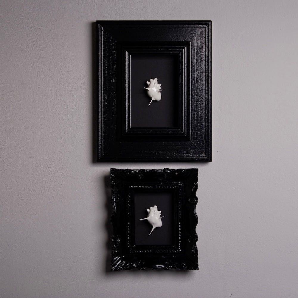 due quadretti con miniatura cuore anatomico spinato, appesi al muro