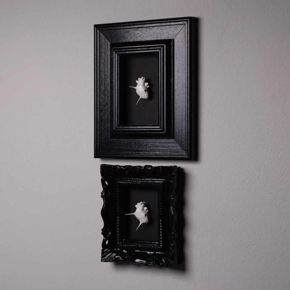 due quadretti con miniature cuori anatomici spinati, appesi al muro