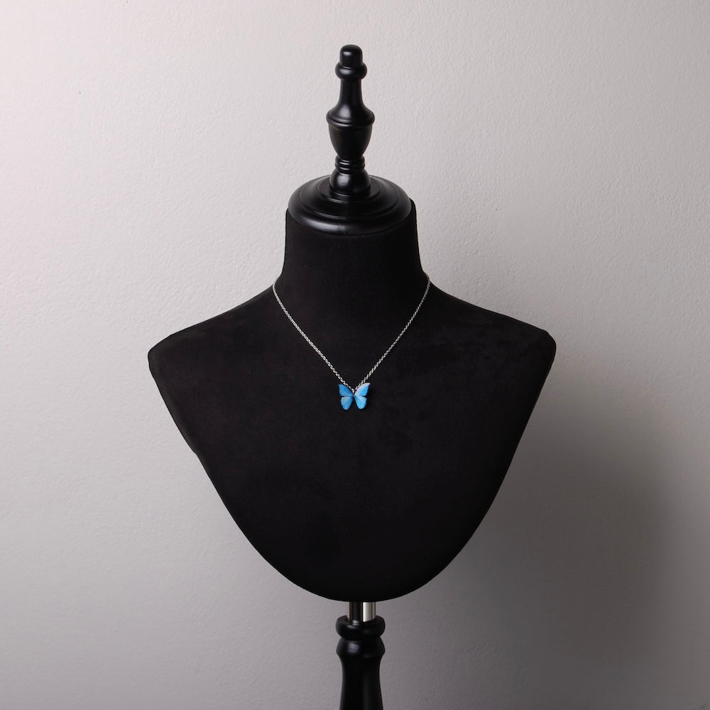 collana catena sottile con pendente farfalla blu in resina su busto espositore in velluto nero