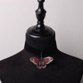 choker in velluto nero con falena cecropia in resina, su busto espositore in velluto nero
