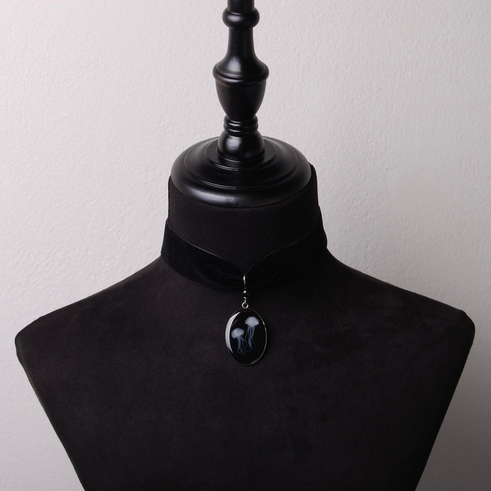 choker in velluto nero con pendente ovale con due meduse marine inglobate sotto resina, su busto espositore in velluto nero