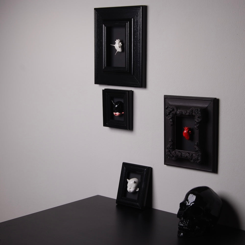 vari quadretti con cuori e teste di bambole appesi e appoggiati su un tavolo