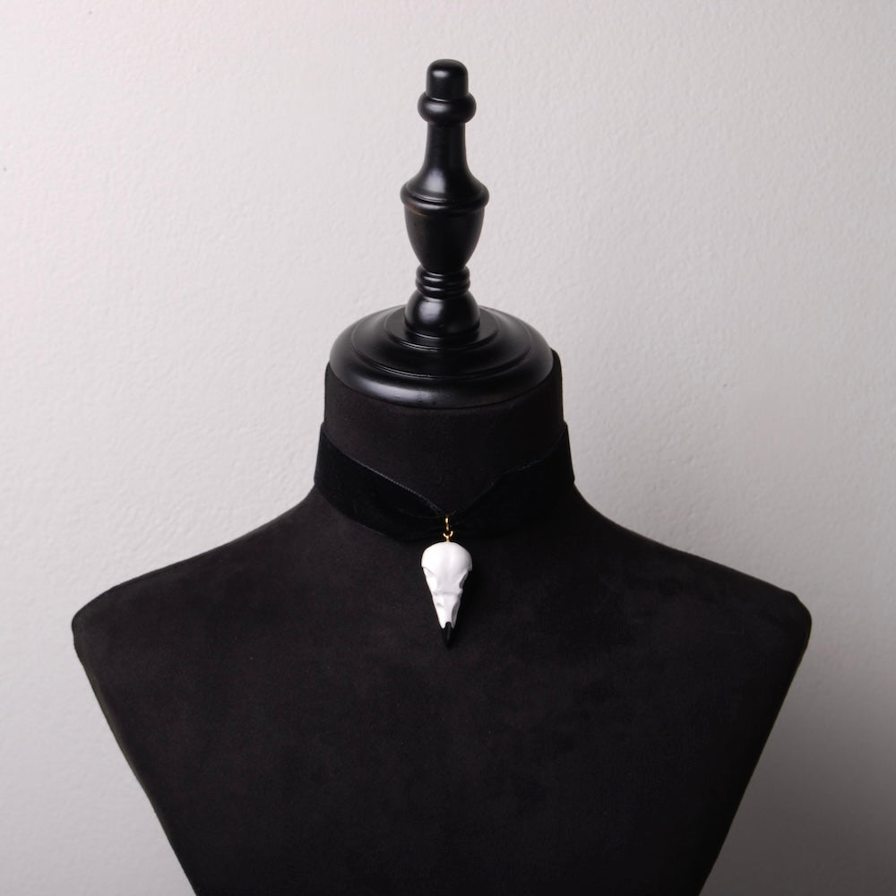choker in velluto nero con pendente teschio di corvo, su busto espositore in velluto nero