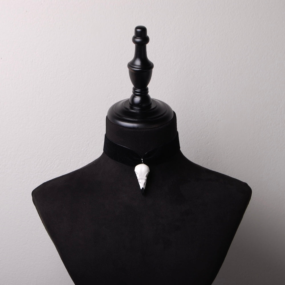 choker in velluto nero con pendente teschio di corvo, su busto espositore in velluto nero