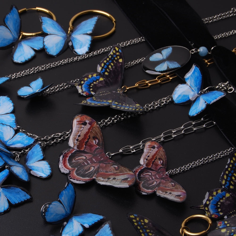 molte collane con farfalle falene poggiate insieme su un piano