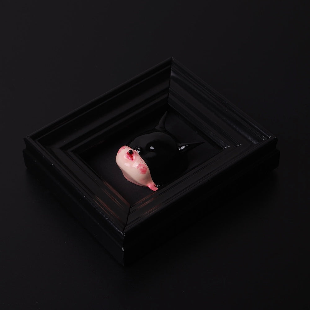 quadretto nero con testa di bambola con maschera nera e corna vista dall'alto 3/4