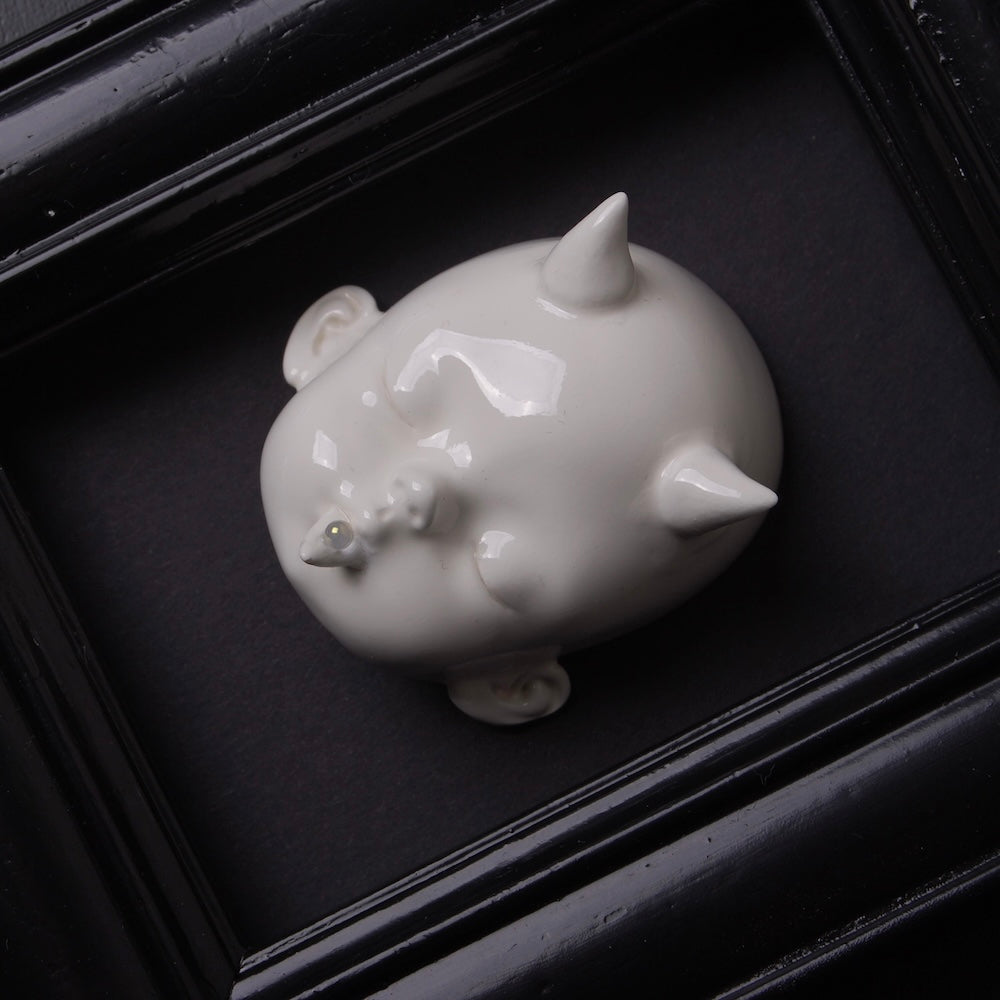 testa di bambola bianca con corna dentro ad un quadretto nero vista dall'alto obliqua