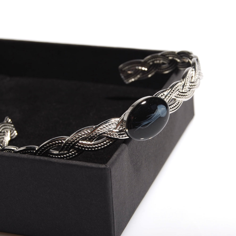 bracciale rigido con cameo centrale con micro medusa inglobata sotto resina, poggiato su una scatolina