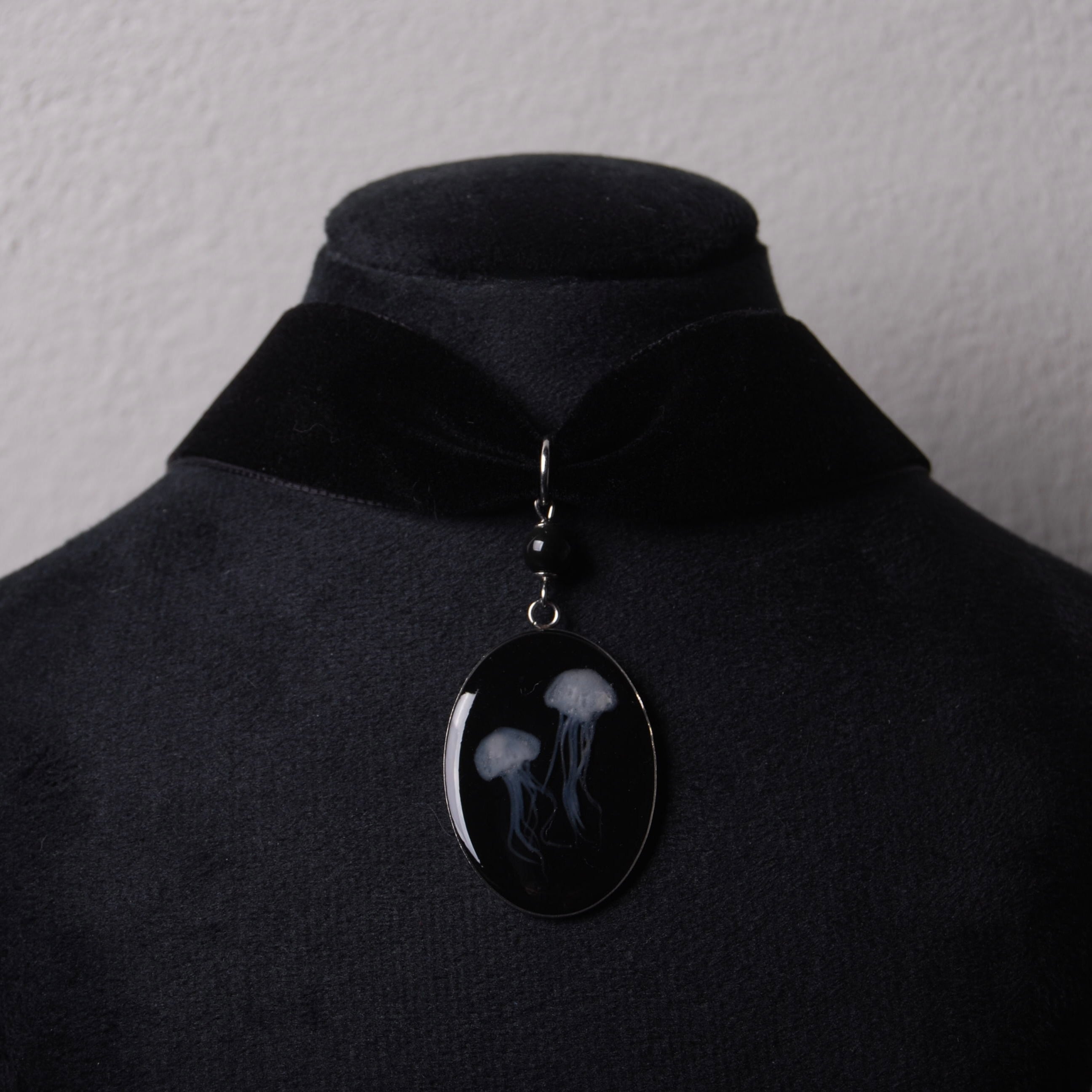 choker in velluto nero con pendente ovale con meduse e perla di ossidiana nera su espositore per collane