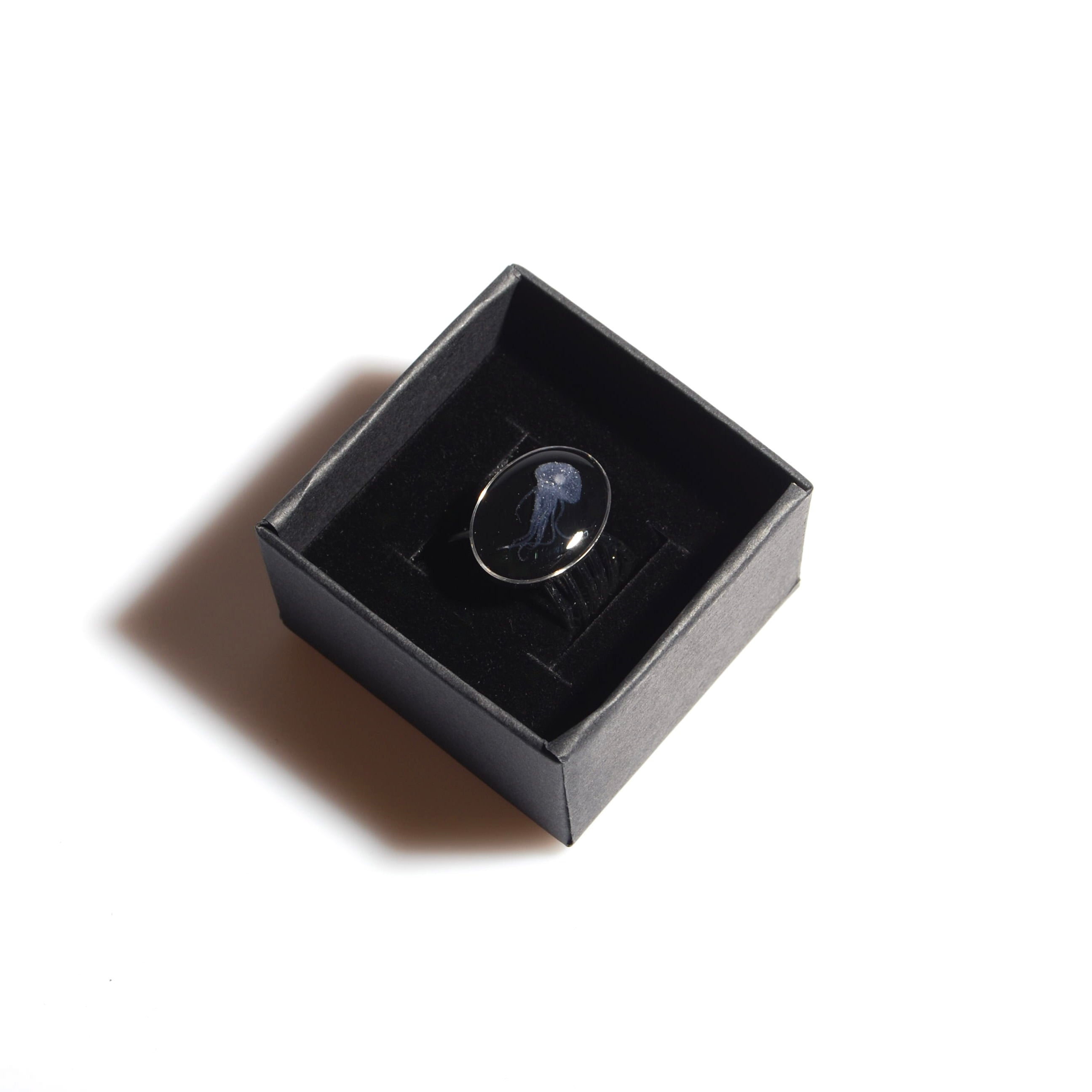 Anello base multipla con ovale con micro medusa dentro ad una scatolina nera, vista dall'alto