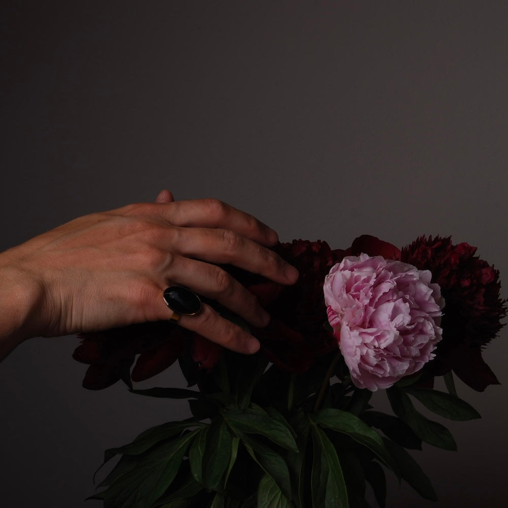 mano con anello ovale che tocca delle peonie in vaso