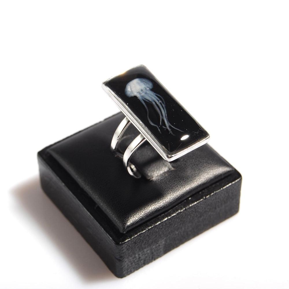 anello rettangolare con medusa inglobata sotto resina su espositore anelli in legno