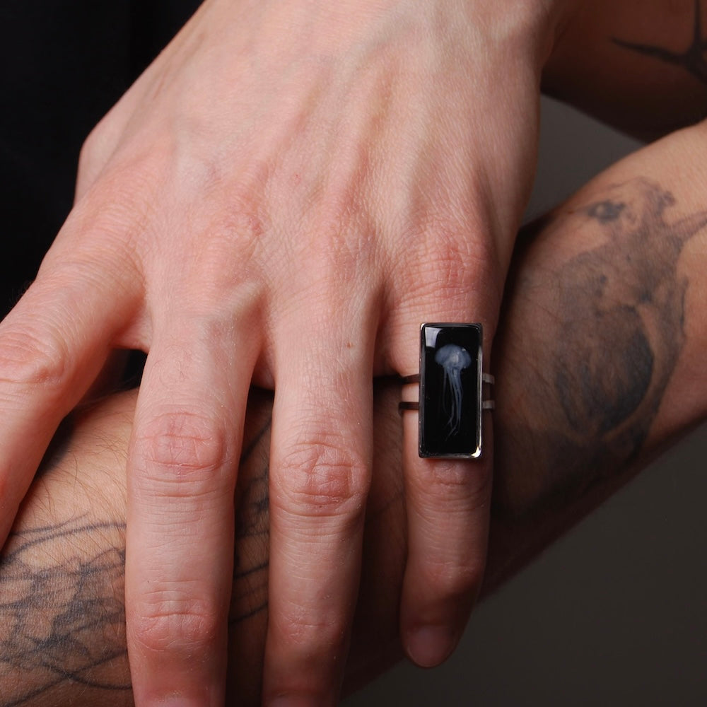 anello rettangolare con medusa sotto resina indossato su una mano maschile