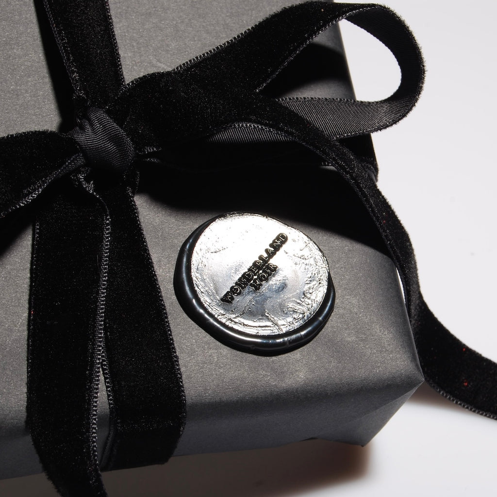 particolare del sigillo in ceralacca di un pacchetto regalo con logo wonderland noir