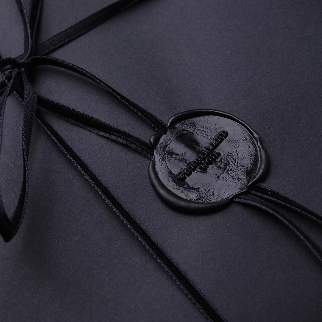 dettaglio del sigillo in ceralacca di un pacchetto regalo con logo wonderland noir