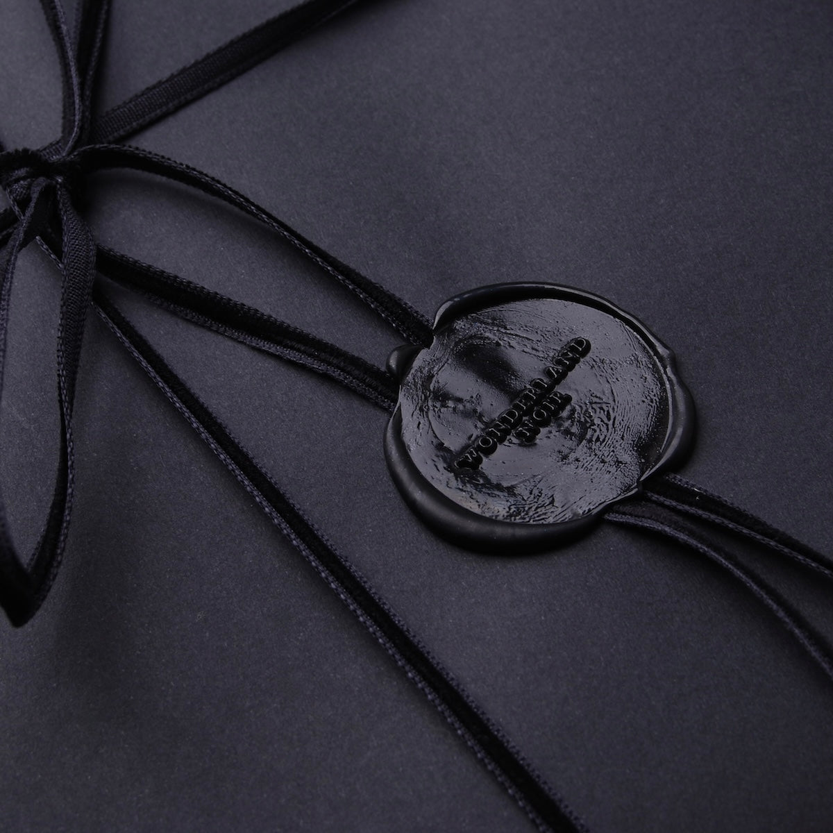 dettaglio del sigillo in ceralacca di un pacchetto regalo con logo wonderland noir