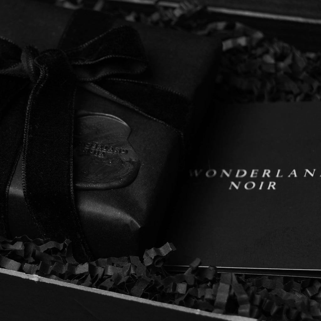 confezione regalo nera con nastro in velluto nero e sigillo in ceralacca dentro ad una scatola da spedizioni