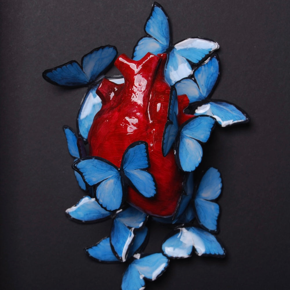 quadretto con cuore anatomico e sciame di farfalle blu, vista frontale