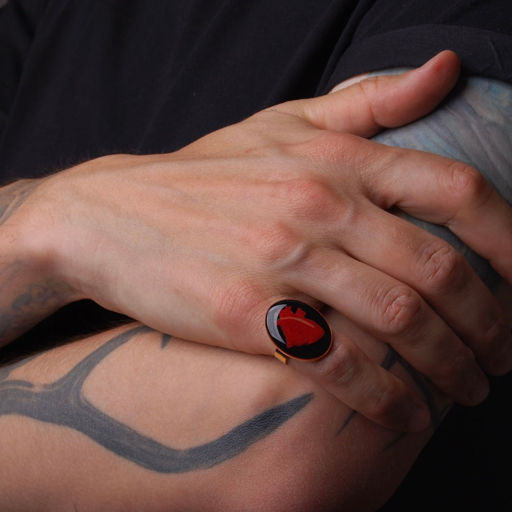 anello con cammeo cuore anatomico indossato su mano maschile poggiata su braccio tatuato