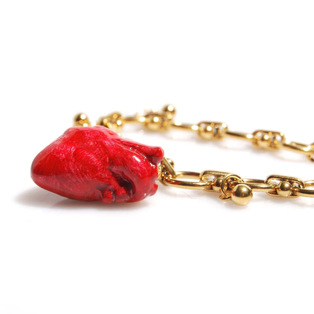 dettaglio del cuore anatomico rosso appeso a un bracciale con catena spessa
