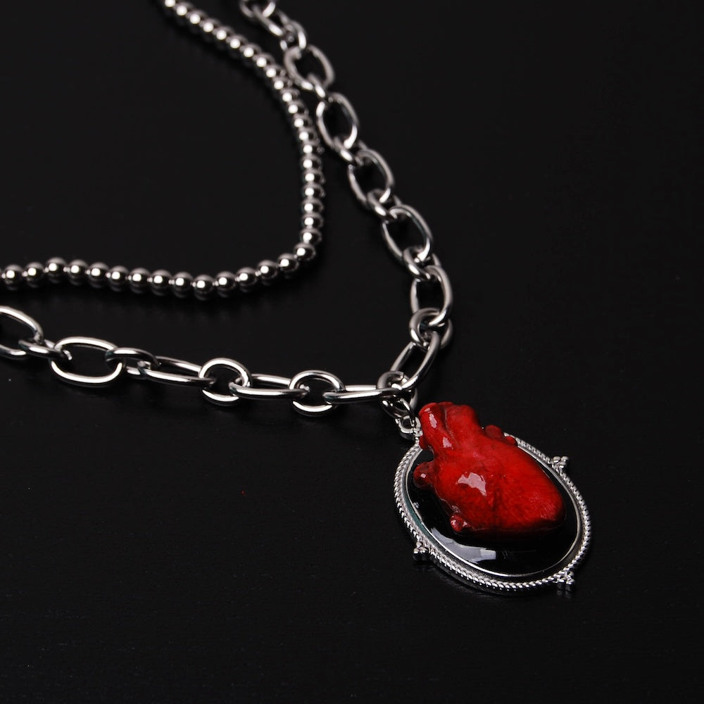 collana a catena doppia con pendente ovale con cuore anatomico rosso, vista 3/4 del pendente