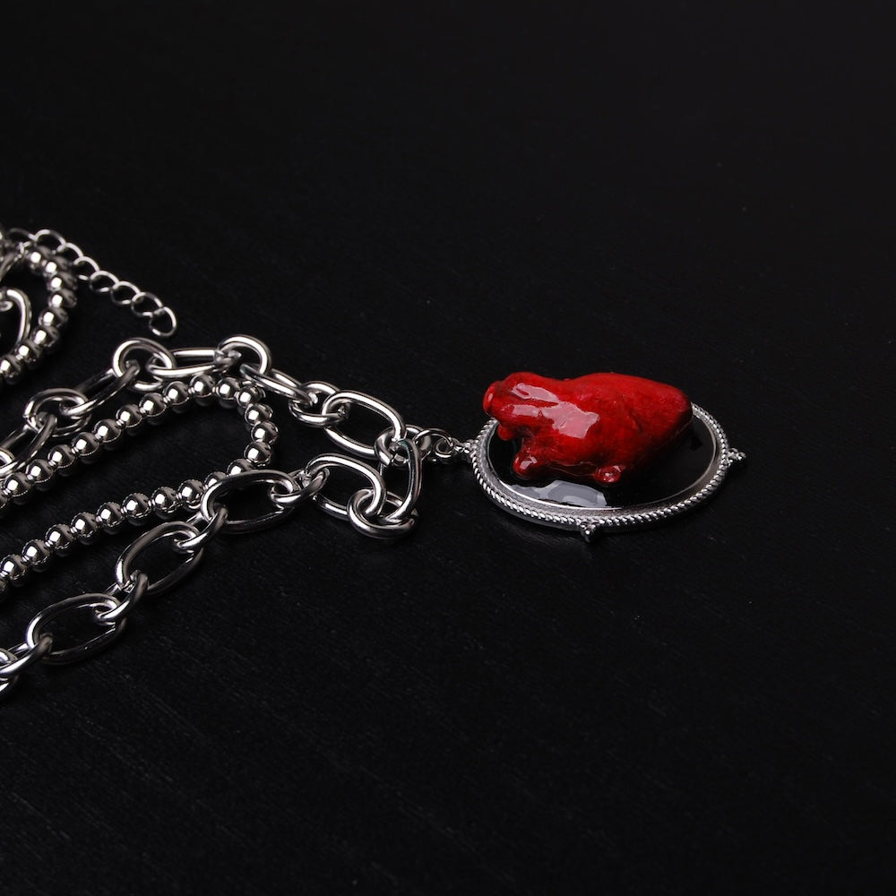 collana a catena doppia con pendente ovale con cuore anatomico rosso, vista laterale del pendente