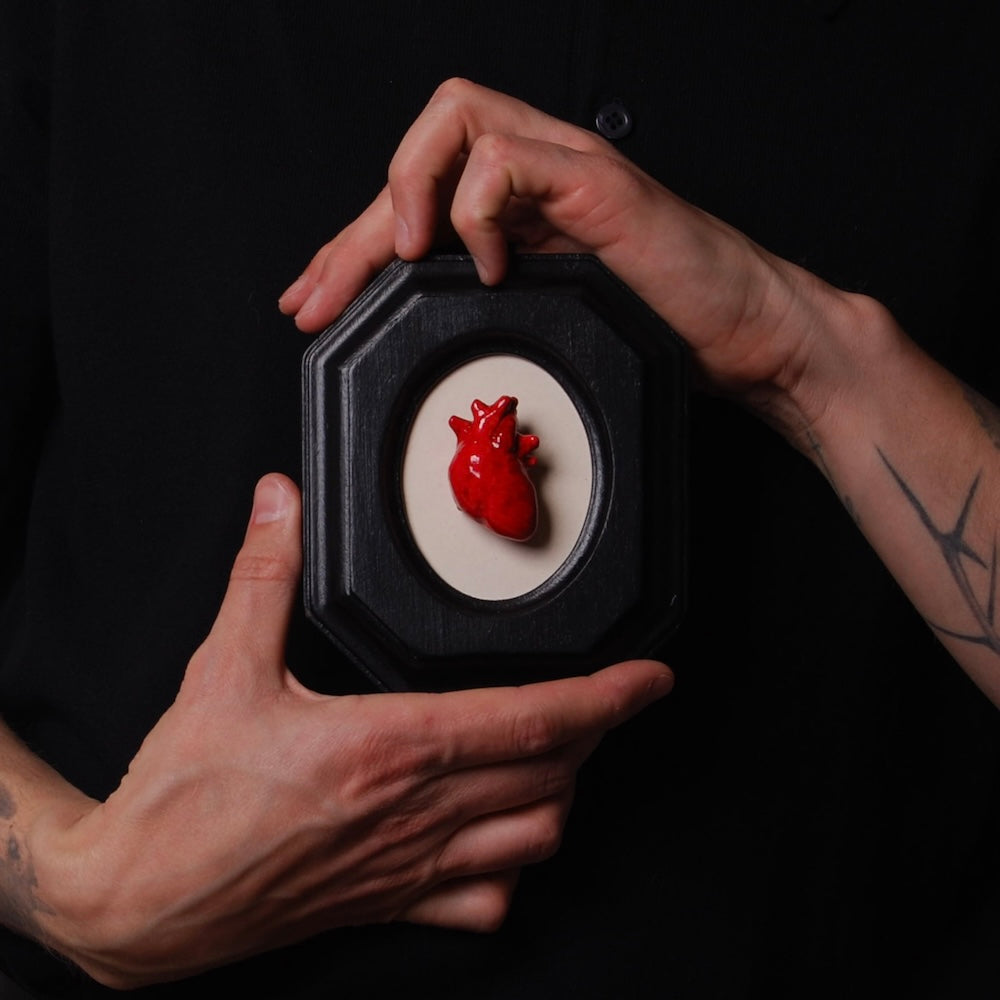 mani che tengono un piccolo quadretto con cuore anatomico