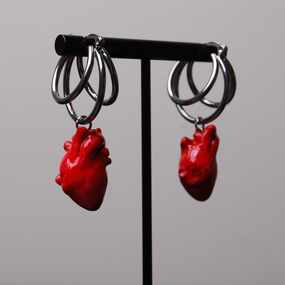 orecchini a triplo cerchio con pendente cuore anatomico appesi su porta orecchini