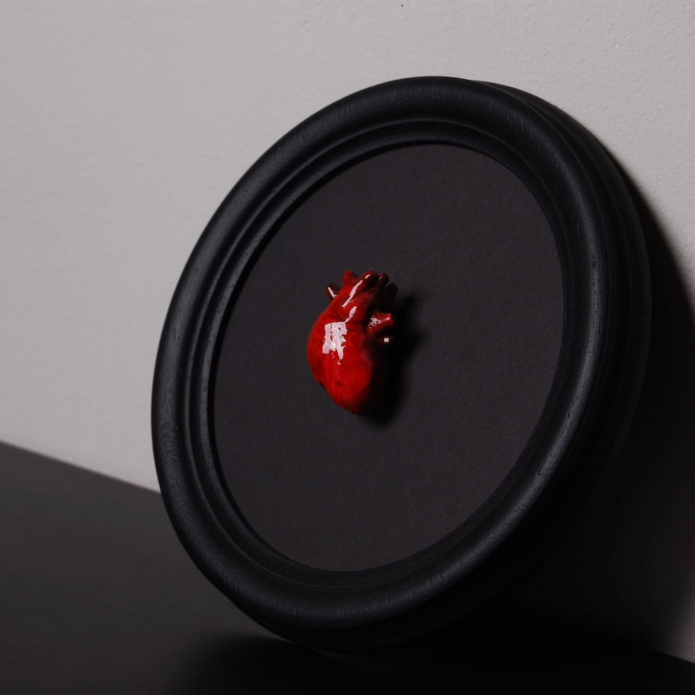 quadretto rotondo con cuore anatomico poggiato su una parete