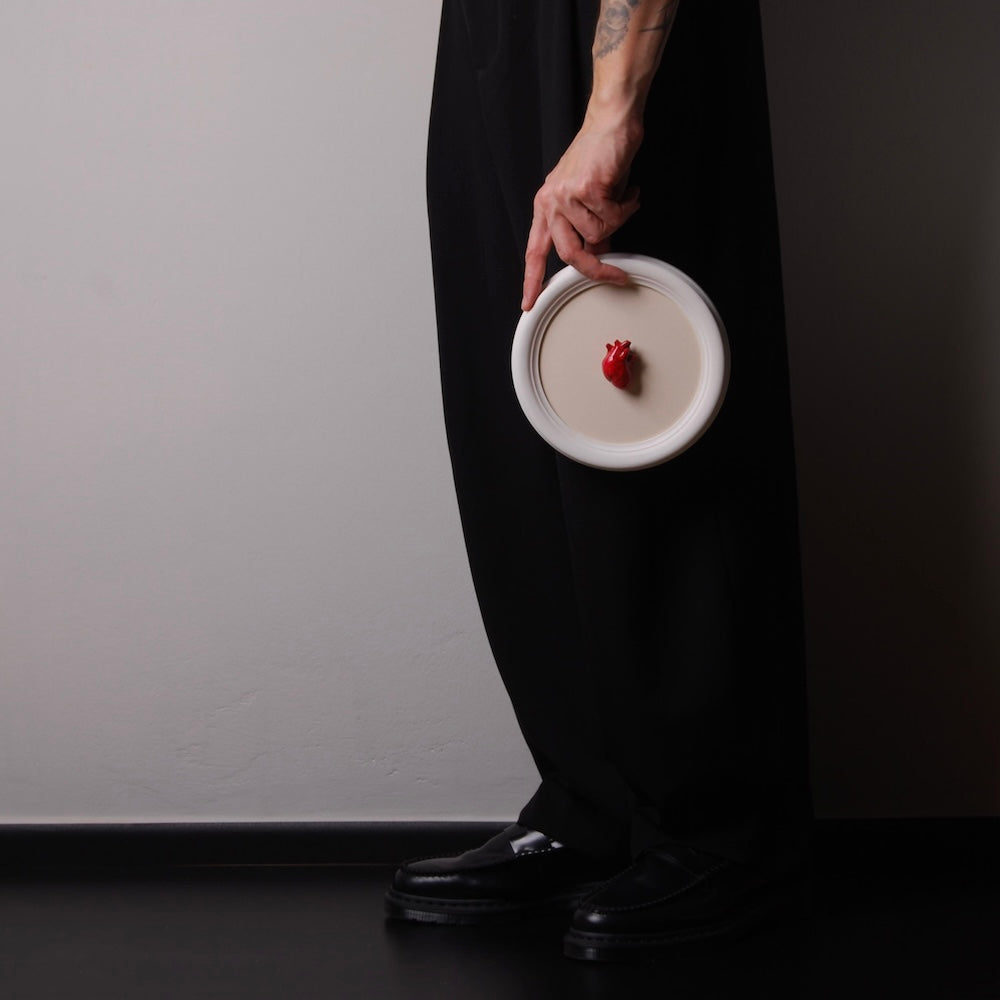 mano che tiene un quadretto rotondo con miniatura cuore anatomico rosso