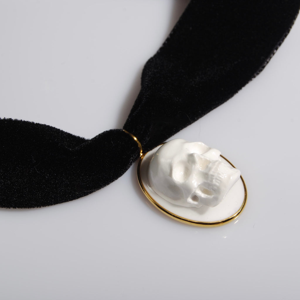 dettaglio del pendente del choker in velluto nero con pendente ovale con teschio bianco stile cammeo, vista 3/4