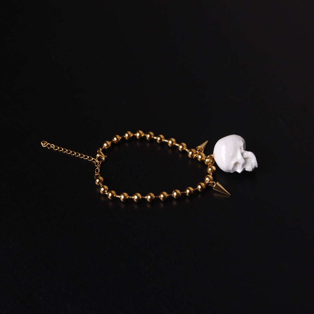bracciale catena a sfere con pendente teschio bianco e punte, vista dall'alto
