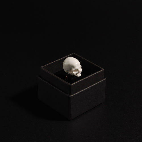 anello con teschio bianco senza mandibola dentro una scatolina nera