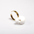 anello con base piatta e teschio bianco, poggiato lateralmente su fondo bianco