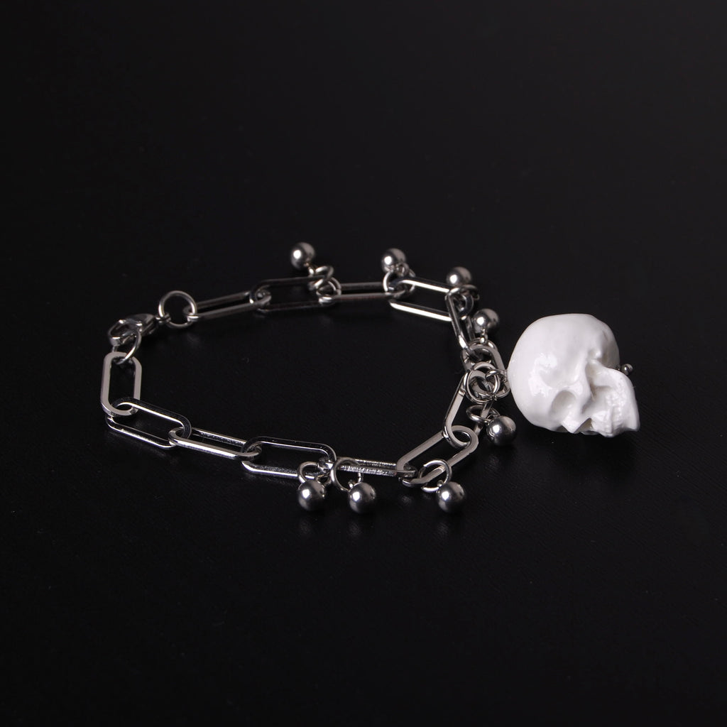 bracciale con pendente teschio bianco e sfere in acciaio, su fondo nero