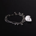 bracciale con pendente teschio bianco e sfere in acciaio, su fondo nero