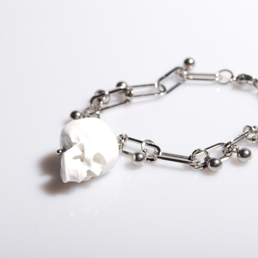 bracciale con pendente teschio bianco e sfere in acciaio, su fondo bianco
