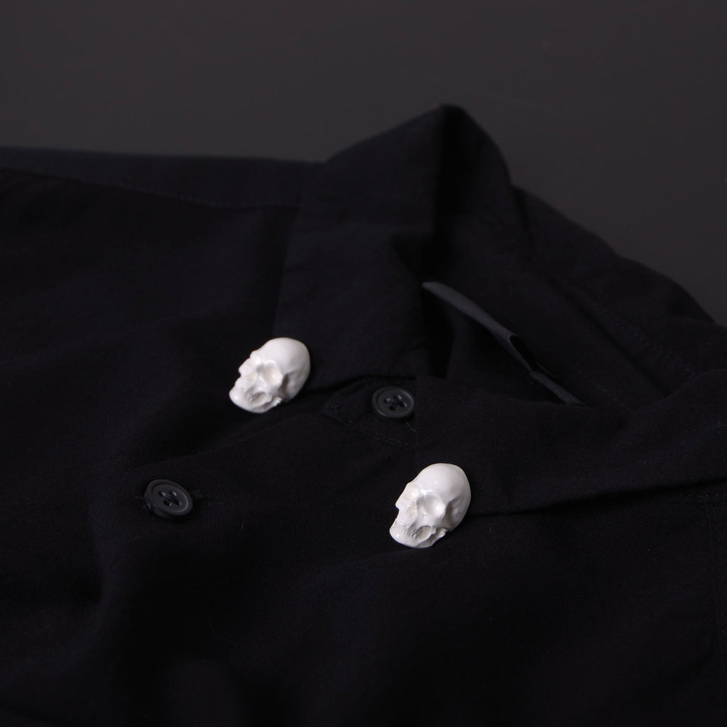 spille a forma di teschio bianco applicate al colletto di una camicia