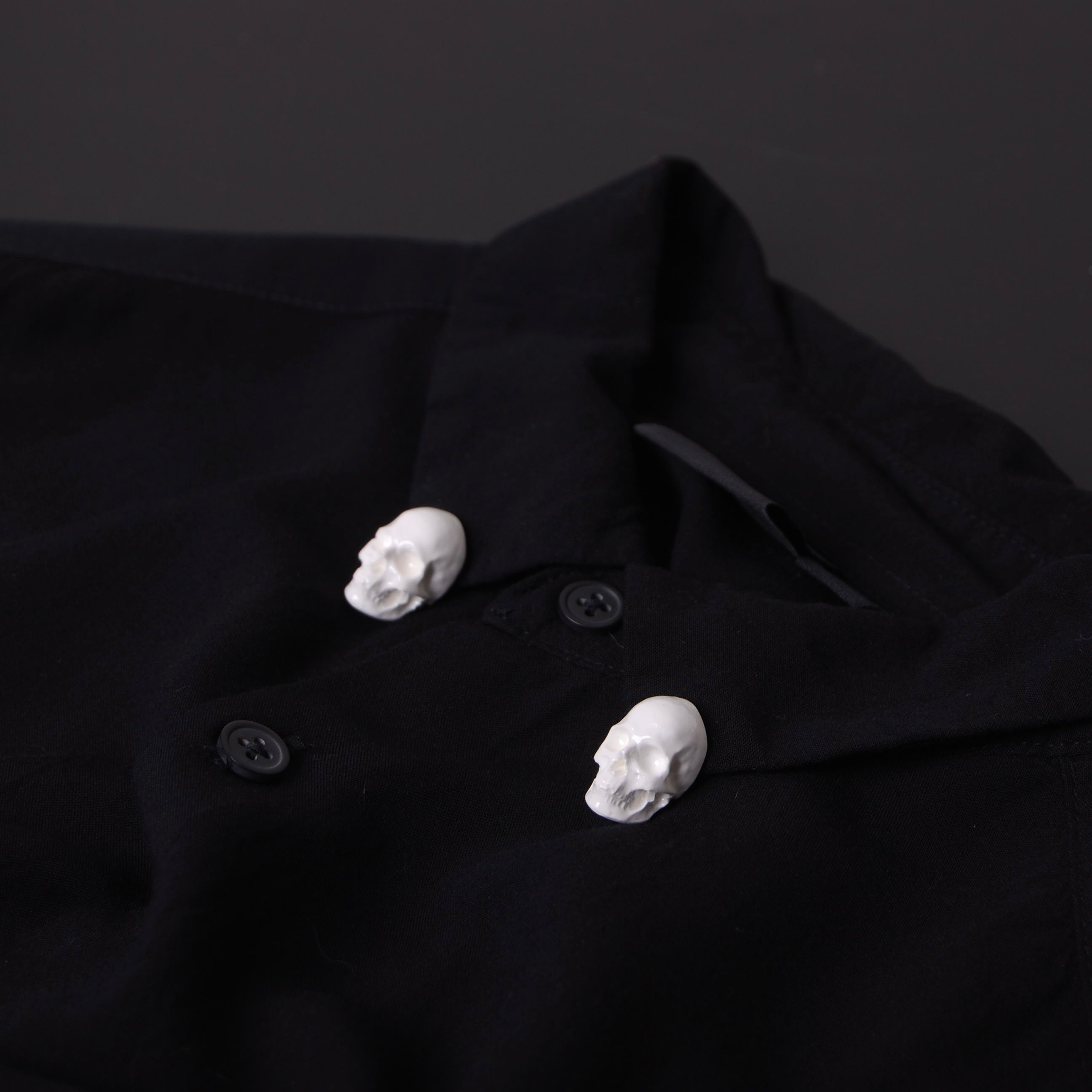 spille a forma di teschio bianco applicate al colletto di una camicia