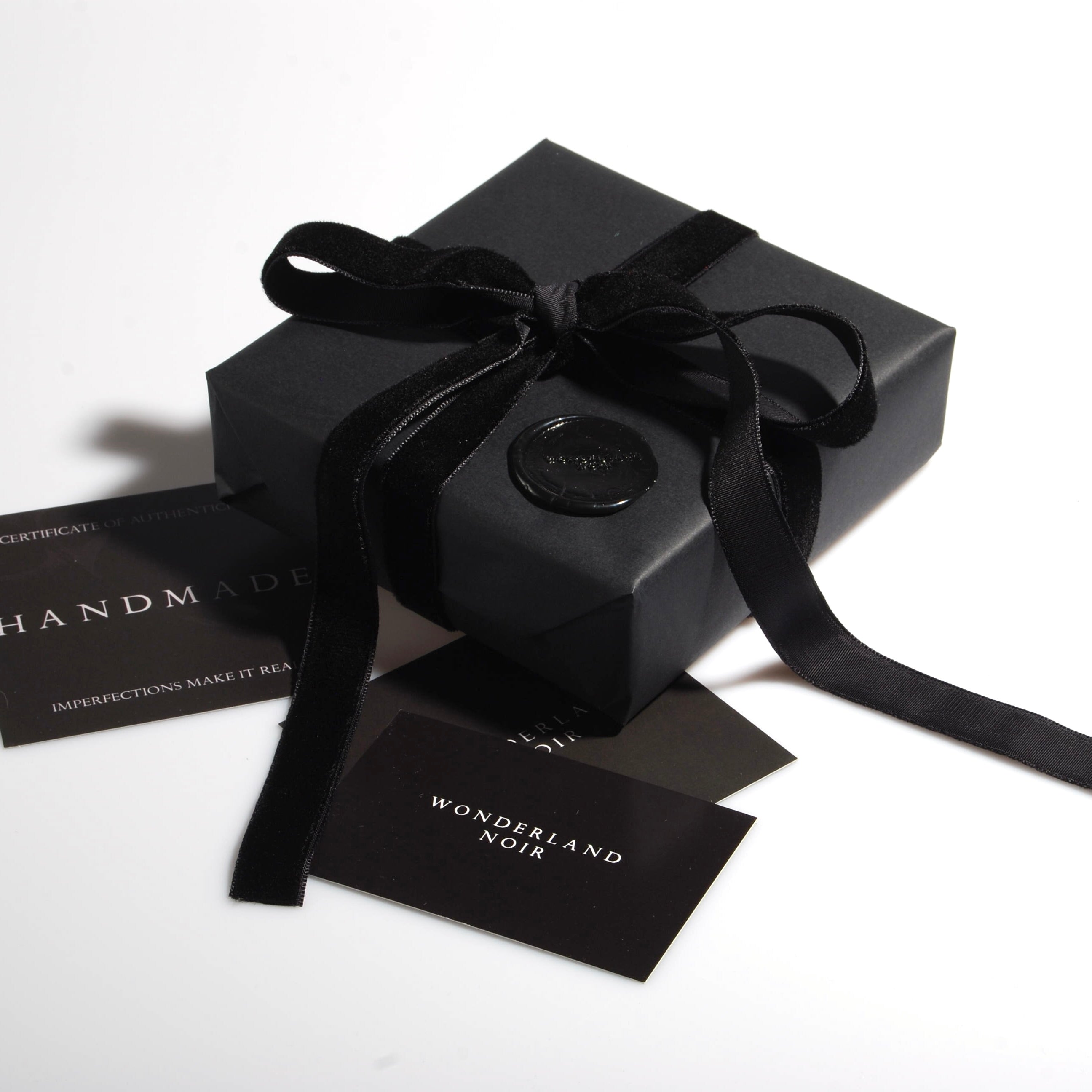 confezione regalo nera con nastro in velluto nero e sigillo in ceralacca con logo e bigliettini das visita