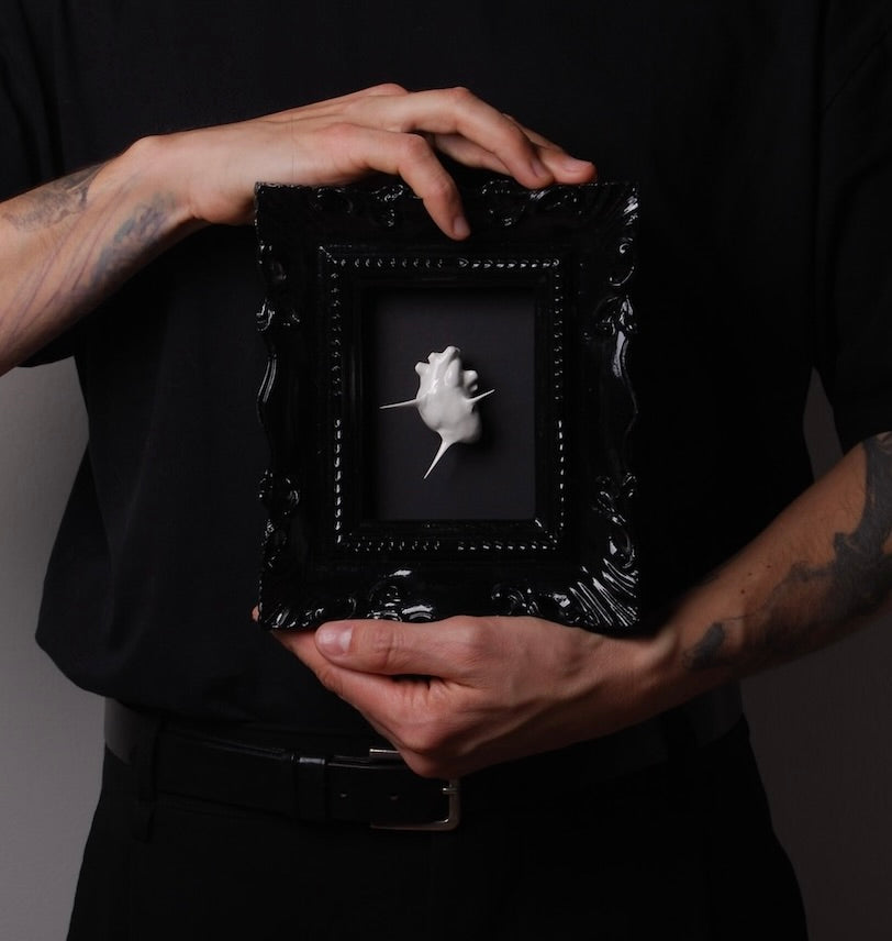 mani che sorreggono un quadretto con miniatura cuore anatomico spinato