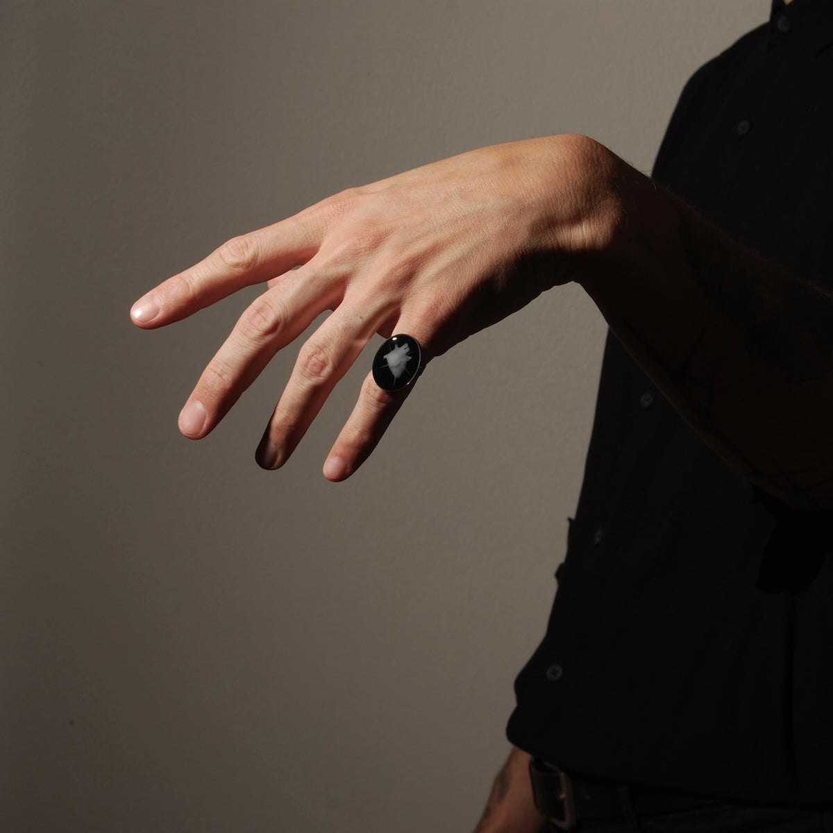 anello ovale con cuore anatomico spinato indossato su una mano in penombra