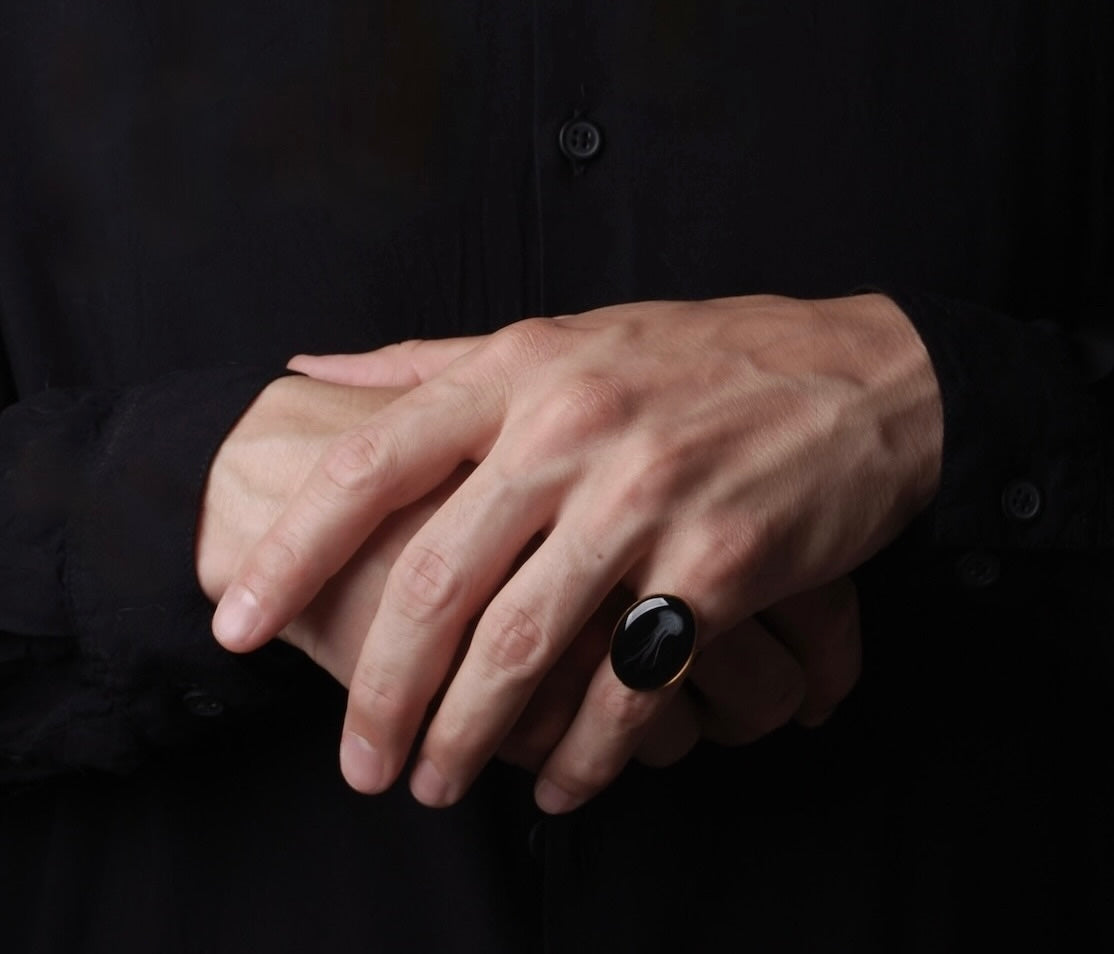 mani che indossano un anello ovale con medusa marina